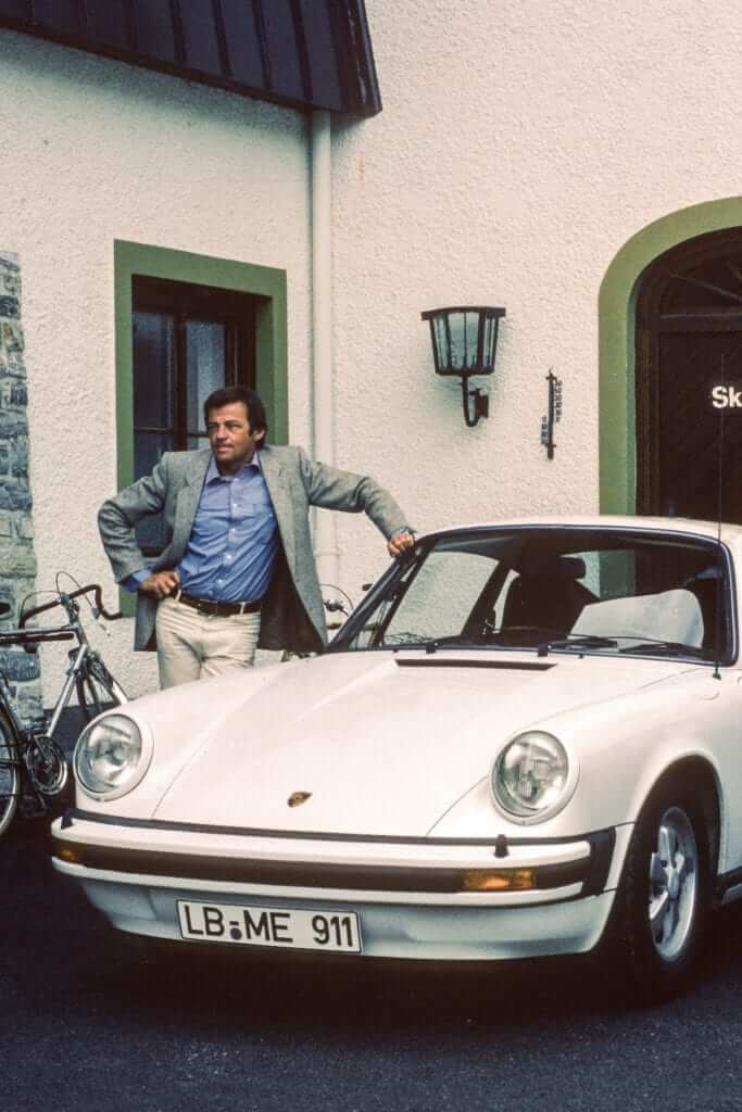 Hans Mezger with his Grand Prix white Porsche Carrera 3.0 in front of the Hotel Porschehof in Zell am See.